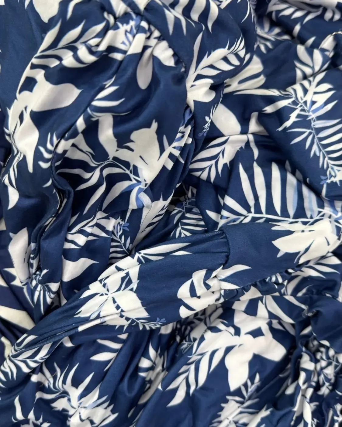 Navy fabric printed with white and pale blue leaves, gathered into folds