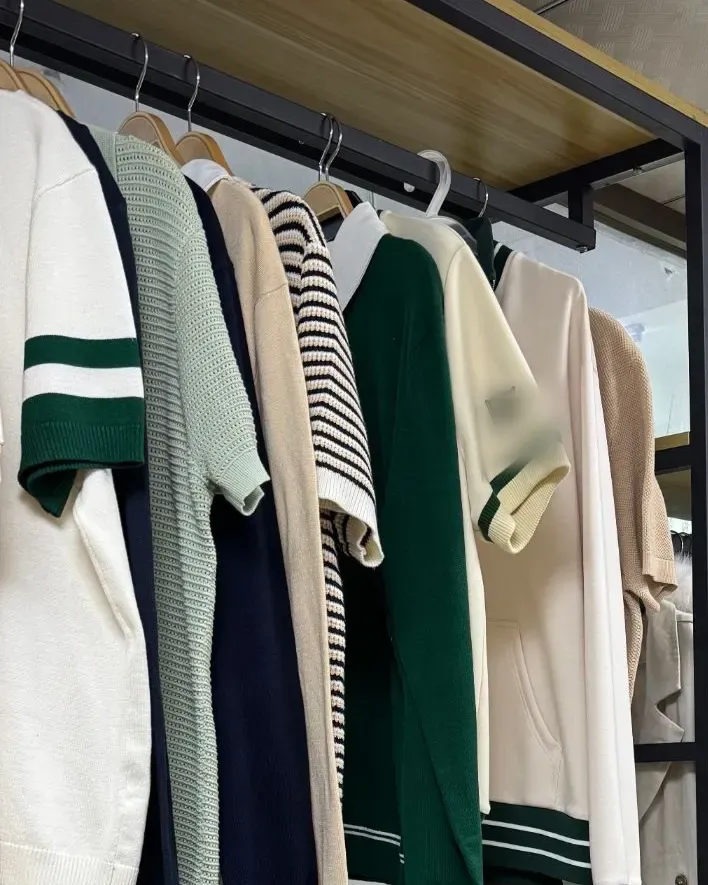 Knitted polos and tops in green, cream and navy stripes hanging on a sample rail