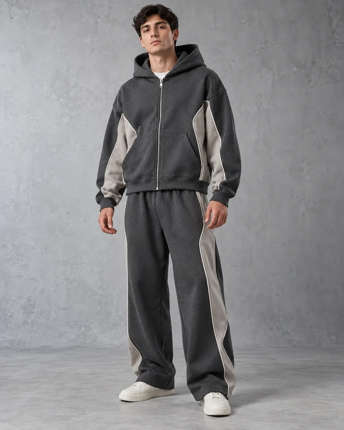 Charcoal zip hoodie and wide-leg trousers worn as a set, with stone panels and contrast piping